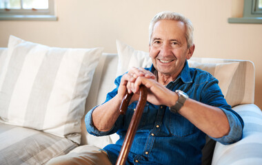 Wall Mural - Im good and so is life. Portrait of a senior man sitting at home with a walking stick.