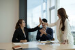 © Natee Meepian - Diverse asian business team celebrating and giving high fives during boardroom meeting. business financial concept