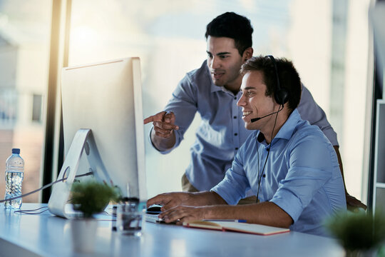 Getting the training he needs to deliver a quality service. Cropped shot of two call centre agents working together in an office.