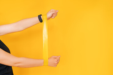 Girl with hands stretching rubber band against yellow background.