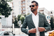 Portrait Of Handsome Confident Stylish Hipster Lambersexual Model.Sexy Modern Man Dressed In Elegant Suit. Fashion Male Posing In The Street Background In Europe City At Sunset. In Sunglasses