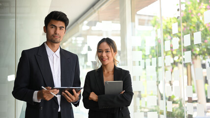 Portrait of two Asian business workers in formal suit with digital tablet