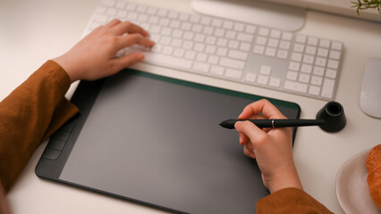 Poster - close-up image, female freelance graphic designer using on graphic tablet