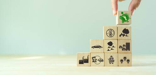 Carbon footprint, low carbon emission concept. Climate changing problems solving goals. Stacking wooden cubes with carbon footprint icon on pollution source icons on grey background,copy space. LCA.