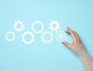 gear wheels and female hand on a blue background. Business structure precise work concept, team unification