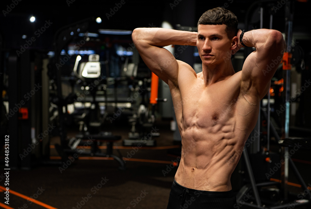 Muscular Guy Holding Arms Behind Neck Flexing Six pack Abs In Gym