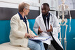 © DC Studio - Senior woman patient signing medical documents while therapist doctor explaining medication treatment during clinical appointment in hospital office. Physician man discussing sickness recovery