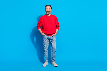 Poster - Full length body size view of attractive cheerful man holding hands in pockets isolated over bright blue color background