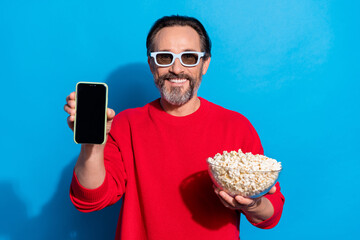 Poster - Photo of laughing good mood man advertising telephone watching film movie isolated on blue color background