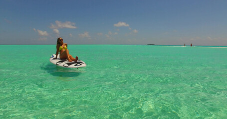 Attractive woman lying on a surfboard floating on the water, Rasdhoo Island, Maldives