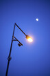 Vertical low angle shot of a lighted street lamp under a moon