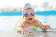© KDdesignphoto - Cute funny toddler girl in colorful swimsuit and sunglasses relaxing on inflatable toy ring floating in pool have fun during summer vacation in tropical resort. Child having fun in swimming pool.
