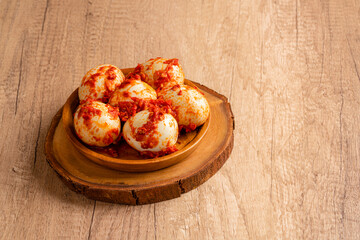 Wall Mural - Indonesian Food Telur balado or boiled eggs with sambal balado. It is popular dish among Indonesia people. served in wood plate on wooden table.