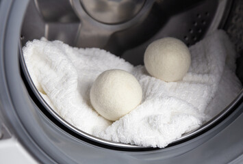 Wall Mural - Using wool dryer balls for more soft clothes while tumble drying in washing machine concept. Discharge static electricity and shorten drying time, save energy.