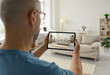© Studio Romantic - House seller giving a virtual video tour around his recently renovated home. Adult man who plans on selling his sofa or his whole studio apartment takes a photo of the stylish interior on a tablet