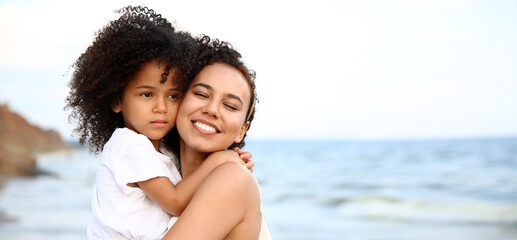 Sticker - African-American girl and her mother hugging on sea beach