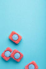 Red and blue tablets for dishwashing machine. Detergents for home hygiene. Dishwasher capsules on blue background.