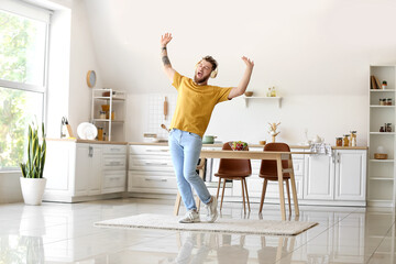 Wall Mural - Cool young man dancing and listening to music at home