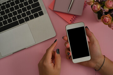 Poster - Top view of hand holding a smartphone leaning to the table have a pen, note books and laptop on the side, for business and technology concept.