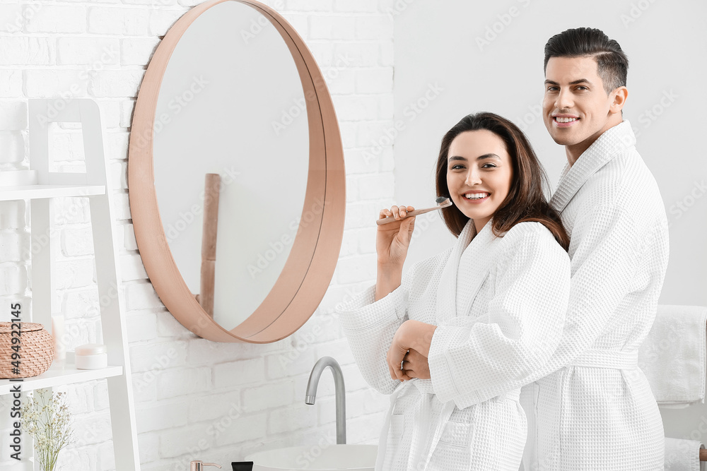 Young couple brushing teeth with activated charcoal tooth paste in bathroom