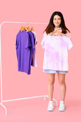 Sticker - Young Asian woman with t-shirt and rack on pink background