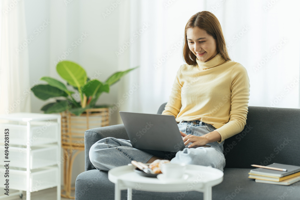 Smiling beautiful young asian ethnicity woman sitting on sofa with ...