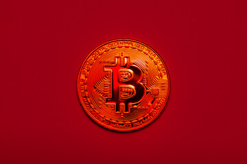 a physical bitcoin coin on a red background. The concept of cryptocurrency.