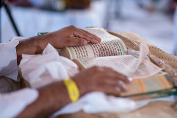 closeup of a man reading the granth sahib at a traditional indian wedding