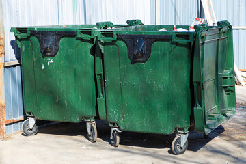 bright, vivid and colorful urban outdoor background of two green plastic garbage containers or trash