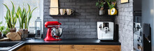 Wooden Clock On A Black Brick Wall In A Trendy Kitchen With A Red Kitchen Robot