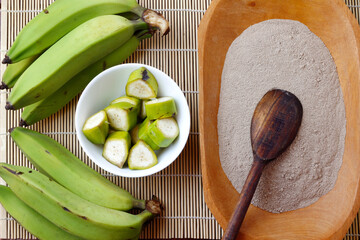 Organic green banana flour, crushed, raw and dry in wooden bowl. gluten free flour