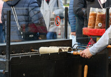 Person baking chimney cake over the charcoal grill at Christmas market in Budapest, Hungary