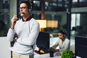 Poster - Lets solve your problems one by one.... Shot of a young call centre agent working late in an office.