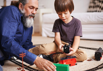 Sticker - Ok grandpa, you be the conductor and Ill drive the train..... Cropped shot of a grandfather watching his grandson play with a toy train.