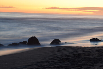 Wall Mural - Sandy beach with stones and a calm sea captured during the golden hour