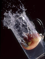 Canvas Print - Vertical shot of splash and apple in a water jug