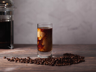 Canvas Print - Cup of cold brew coffee surrounded by coffee beans on a woody table.