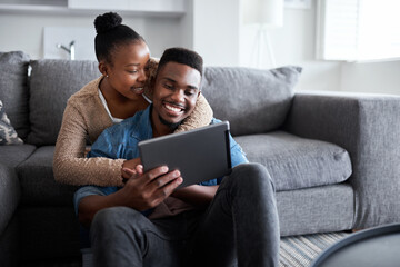 Aufkleber - Sharing in a very special connection. Shot of a young couple using a digital tablet together while relaxing at home.