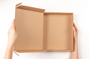 Wall Mural - Top view to female hands opening empty brown cardboard box on white background. Mockup parcel box. Packaging, shopping, delivery concept