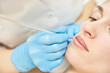 © elenavolf - Permanent makeup. Beauty spa procedure. young woman. Face tattoo. Lip micropigmentation. Professional face microblading. Female cosmetology device. Copyspace. Mouth treatment. Dermatology