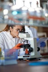 a young female student working with a microscope in a laboratory. science, chemistry, lab, people