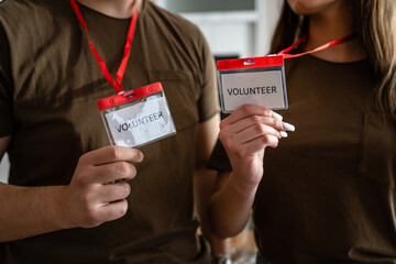 Close up on hands of two unknown man and woman holding id cards with volunteer title working at charity foundation copy space humanitarian aid concept