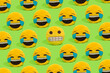 Scheme of yellow smiley pillows laughing at a smiley with a embarrassed grimace on a green background.