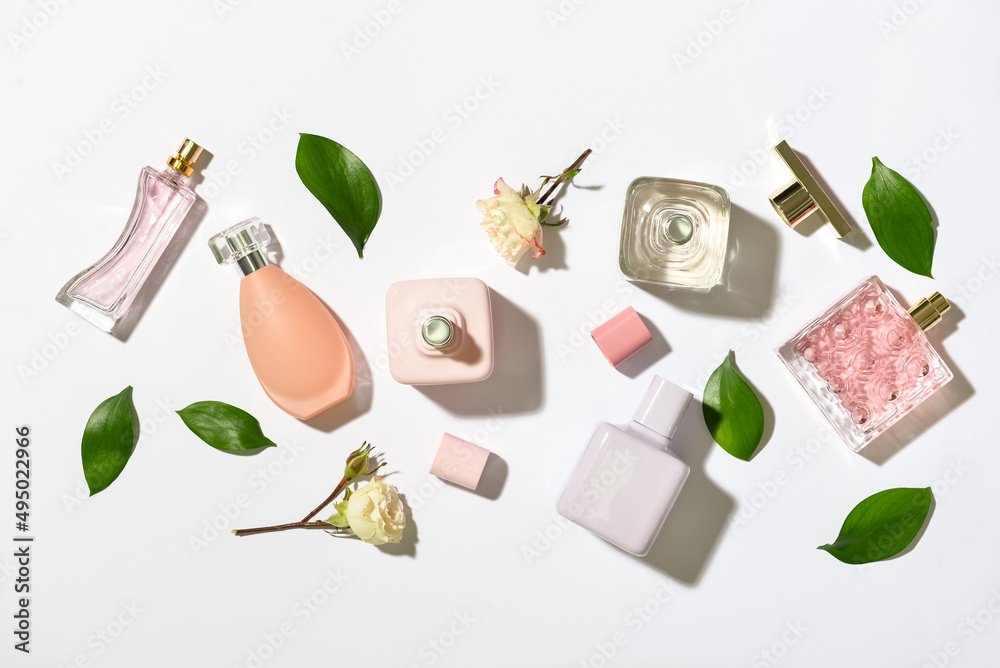 Bottles of floral perfumes on light background, top view