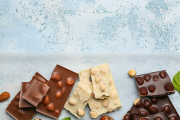 Wall Mural - Pieces of tasty chocolate with nuts on color background