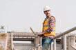 © ztony1971 - Portrait of power engineer wearing safety jacket and hardhat with laptop computer working at outdoor field site that have water spillway  of hydro power dam electrical generator at the background.