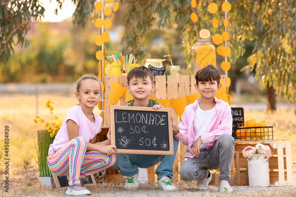 Cute children selling lemonade in park