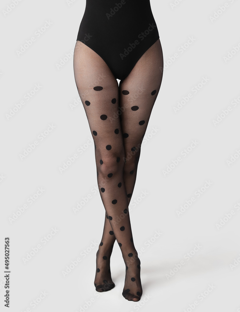 Beautiful young woman in black tights on light background