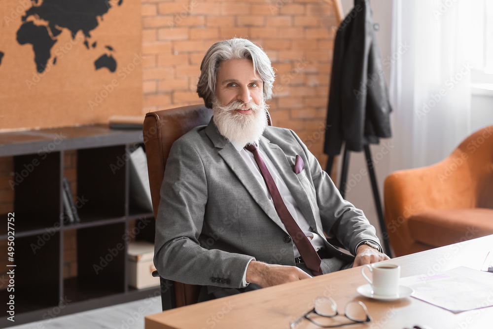 Handsome mature bearded businessman working in office