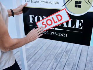 Poster - Another property sold. High angle shot of an unrecognizable female real estate agent sticking a sold sign over a for sale board.